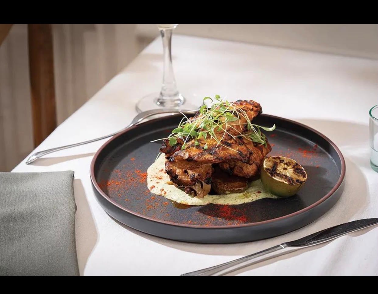 Plated grilled meat with herbs and charred lime
